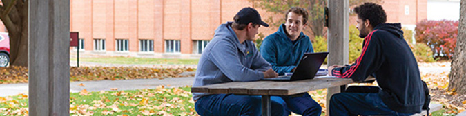Photo of students sitting at picnic table